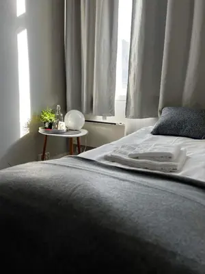 a bedroom with a bed and a nightstand next to a window at Leirvik Vandrehjem in Leirvik