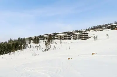 a ski lodge on a snowy hill with trees at Hafjell Front 220D 8pers, Ski inout , Downhill Bike in Hafjell