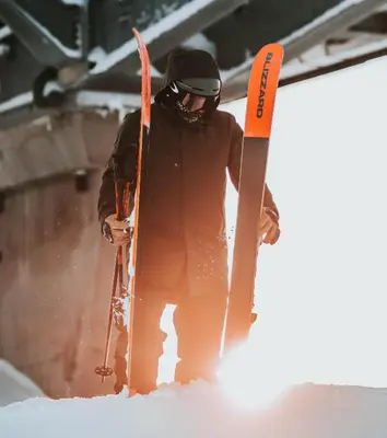 a man standing in the snow holding skis at Highland Lodge Fjellandsby in Geilo