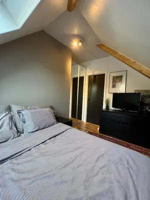 a bedroom with a large bed and a flat screen tv at Central Two Room Apartment! in Trondheim