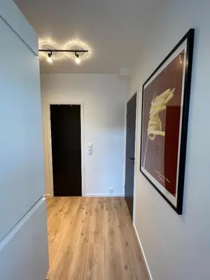 an empty hallway with a painting on the wall and a black door at Central Two Room Apartment! in Trondheim