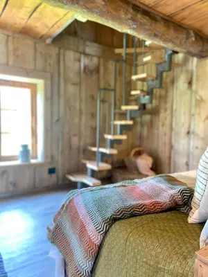 a room with a bed and stairs in a cabin at Kufjøset in Skjåk