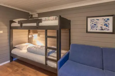 a bedroom with bunk beds and a blue couch at Trysil Alpin 40A in Trysil