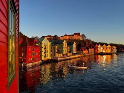a river with colorful buildings and a boat in the water at Central Seafront Apartments with Parking and Self Check-In! in Bergen