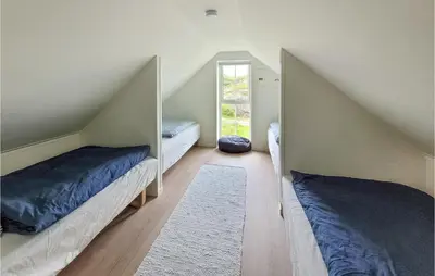 a attic bedroom with two beds and a mirror at 3 Bedroom Lovely Home In Stolmen