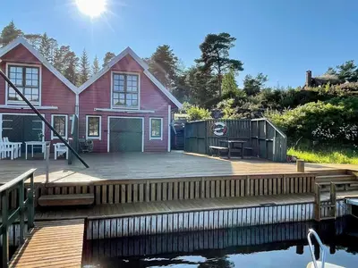 a red house with a dock next to the water at 9 person holiday home in MOSTERHAMN-By Traum in Mosterhamn