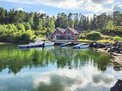 a house on a river with boats in the water at 9 person holiday home in MOSTERHAMN-By Traum in Mosterhamn