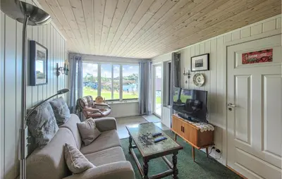 a living room with a couch and a tv at Nice Home In Bremnes With Wifi in Bremnes