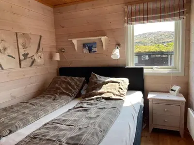 a bedroom with two beds and a window at Panoramahytte in Norheimsund