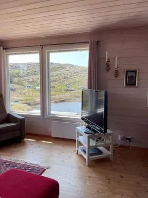 a living room with a tv and a large window at Panoramahytte in Norheimsund