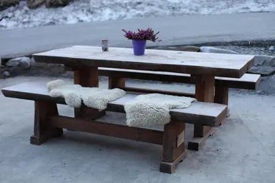 a wooden picnic table with two seats and a plant at Hordatun Apartments in Røldal