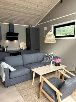 a living room with a blue couch and a table at Kavliskogen panorama in Isfjorden