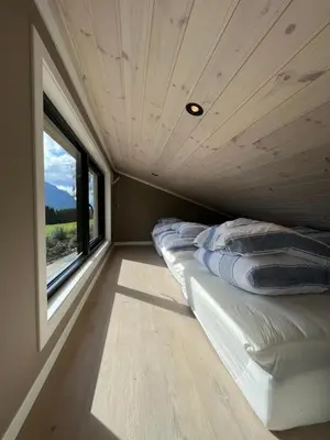a bedroom in a tiny house with a window at Kavliskogen panorama in Isfjorden