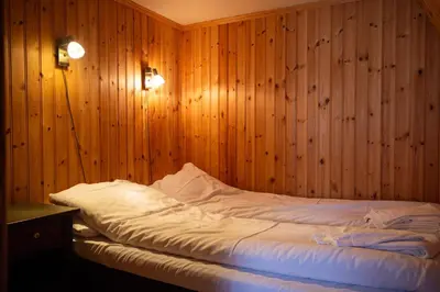a bed in a room with wood paneled walls at Houmbgaarden in Røros
