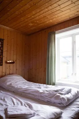 a bed in a wooden room with a window at Houmbgaarden in Røros