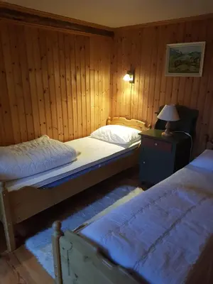 a bedroom with two beds and a lamp on a table at Houmbgaarden in Røros