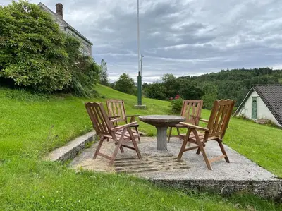 three chairs and a table in a yard at Feriehus i landlige område med nydelig utsikt in Leirvik