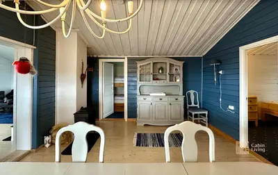 a dining room with two white chairs and a chandelier at Large cabin Sjusjøen XC ski in out & lovely view in Ringsaker