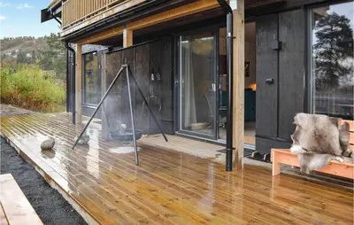 a house with a wooden deck with glass doors at Cozy Home In Rauland With Sauna in Torvetjørn