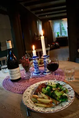 a table with a plate of food and a bottle of wine at The Olav-house from 1840, at farm Ellingbø in Vang I Valdres