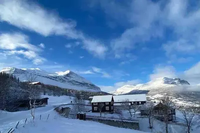 a house in the snow with mountains in the background at The Olav-house from 1840, at farm Ellingbø in Vang I Valdres