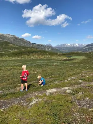 two little boys standing in a grassy field at The Olav-house from 1840, at farm Ellingbø in Vang I Valdres