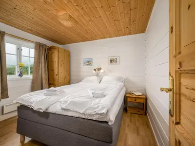 a bedroom with a bed with white sheets and a wooden ceiling at Chalet Hagehytta by Interhome in Utvik