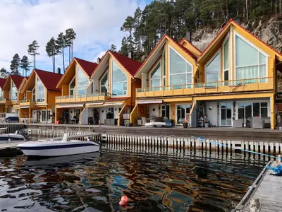 a row of houses on the water with a boat at Apartment Heningen by Interhome in Uggdal