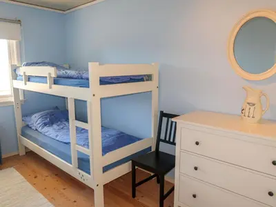 a bedroom with a bunk bed with a mirror and a chair at Holiday Home Villa Hjartnes by Interhome in Hjartåker