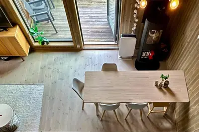 a wooden table and chairs in a room with a window at Sjusjøen ski in out, ski storage, Wifi, grill & fireplace, modern apartment! in Sjusjøen