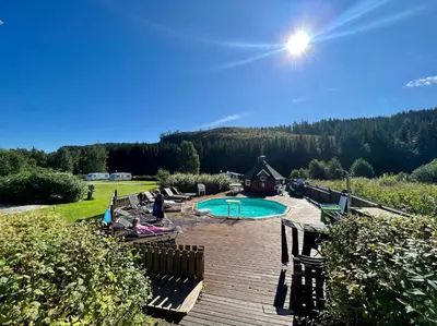 a swimming pool on a wooden deck with a house at Gullvåg Camping Nyberg in Soknedal