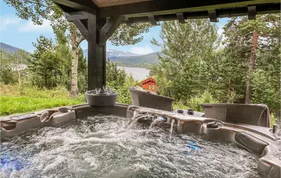 a hot tub in a backyard with chairs and water at Nice Home In Sykkylven With Kitchen in Sykkylven