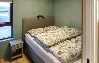a bed in a small room with a bedskirtspectspectssenalsenalsenalsenal at Nice Home In Straumgjerde in Riksem