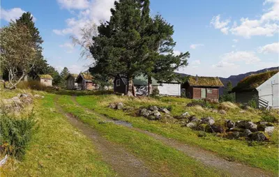 a dirt road in a field with houses and a tree at Nice Home In Straumgjerde in Riksem