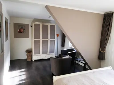 a room with a staircase with a bed and a chair at Løvheim Gjestehus in Sauland