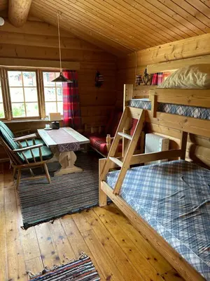 a room with two bunk beds and a table in a cabin at Atnasjø Kafe AS in Sollia