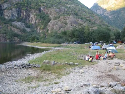 a group of people sitting on the rocks near a lake at Sæbø Camping in Eidfjord