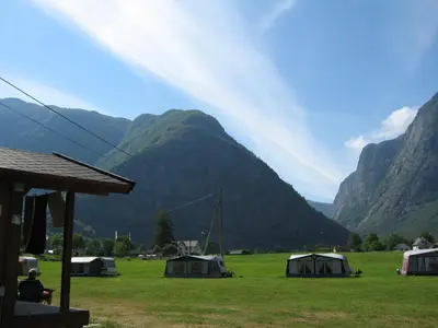 a group of tents in a field with mountains in the background at Sæbø Camping in Eidfjord