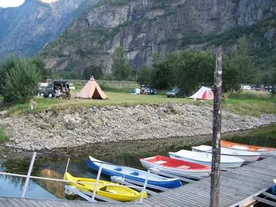 a group of boats sitting on the water near a mountain at Sæbø Camping in Eidfjord