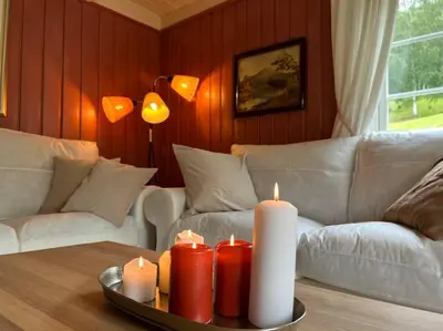 a living room with a couch and candles on a table at « SoFly Cottage », le charme pur in Noresund