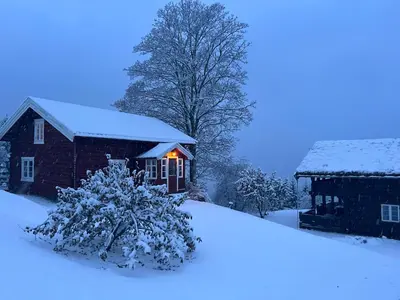 a house covered in snow next to a building at « SoFly Cottage », le charme pur in Noresund