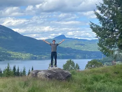 a man standing on a rock with his arms outstretched at « SoFly Cottage », le charme pur in Noresund