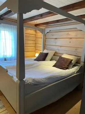 a bed in a room with a wooden wall at Solsetra - Mountain Majesty Family Log Cabin in Hovden