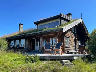 a log cabin with two chairs on the porch at Solsetra - Mountain Majesty Family Log Cabin in Hovden