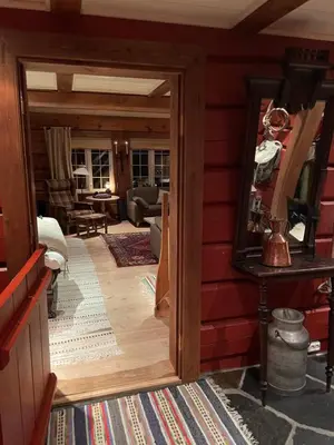 an open door to a living room with red walls at Solsetra - Mountain Majesty Family Log Cabin in Hovden