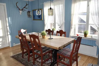 a dining room with a wooden table and chairs at Nedre Stensgården in Røros