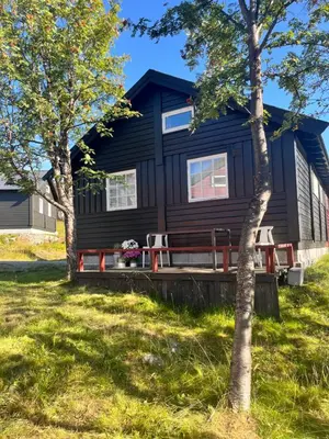 a black cabin with a picnic table in front of it at River view in Hovet