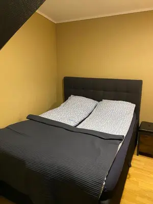 a bed with a black headboard in a room at Leilighet med sydvendt balkong in Ålesund