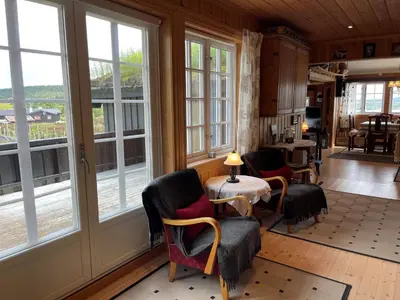 a living room with windows and a table and chairs at Snikkerplassen - cabin with amazing view and hiking opportunities in Sør-Fron