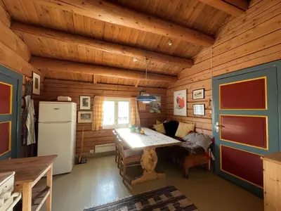 a wooden cabin with a table and a refrigerator at Elveseter - log cabin with an amazing view in Venabygd